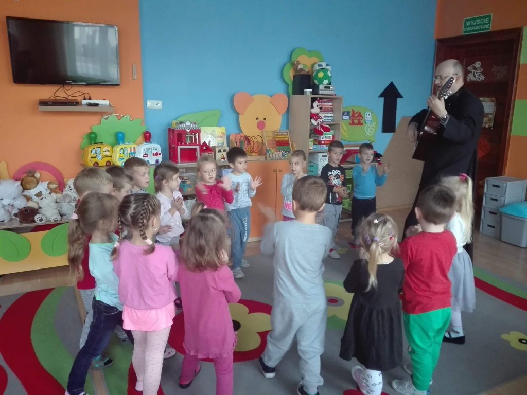 dzieci śpiewają z księdzem